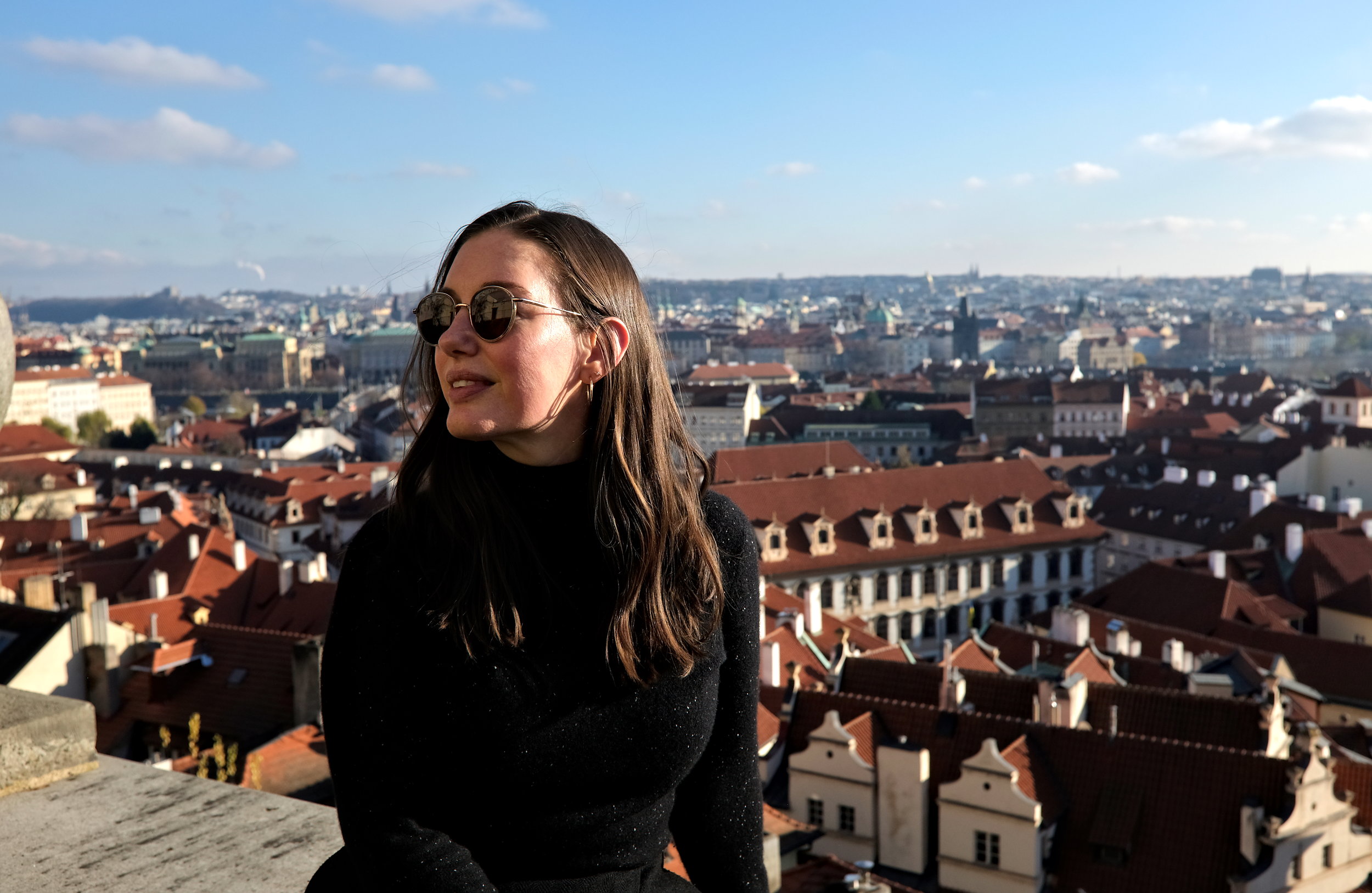 Alyssa wears a black sweater with Prague in the background