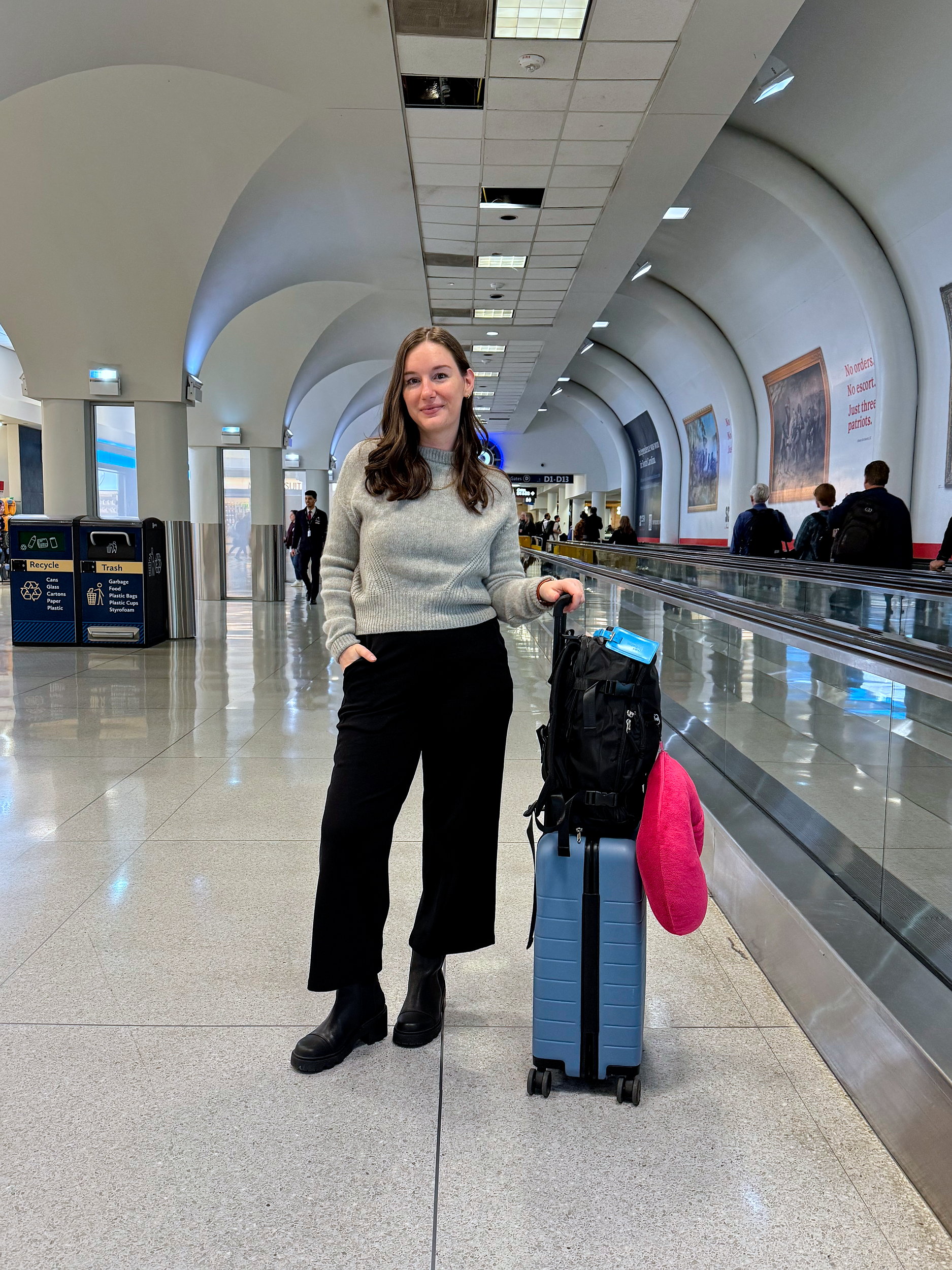 Alyssa in the Charlotte airport with her backpack  and pillow for a Lufthansa flight