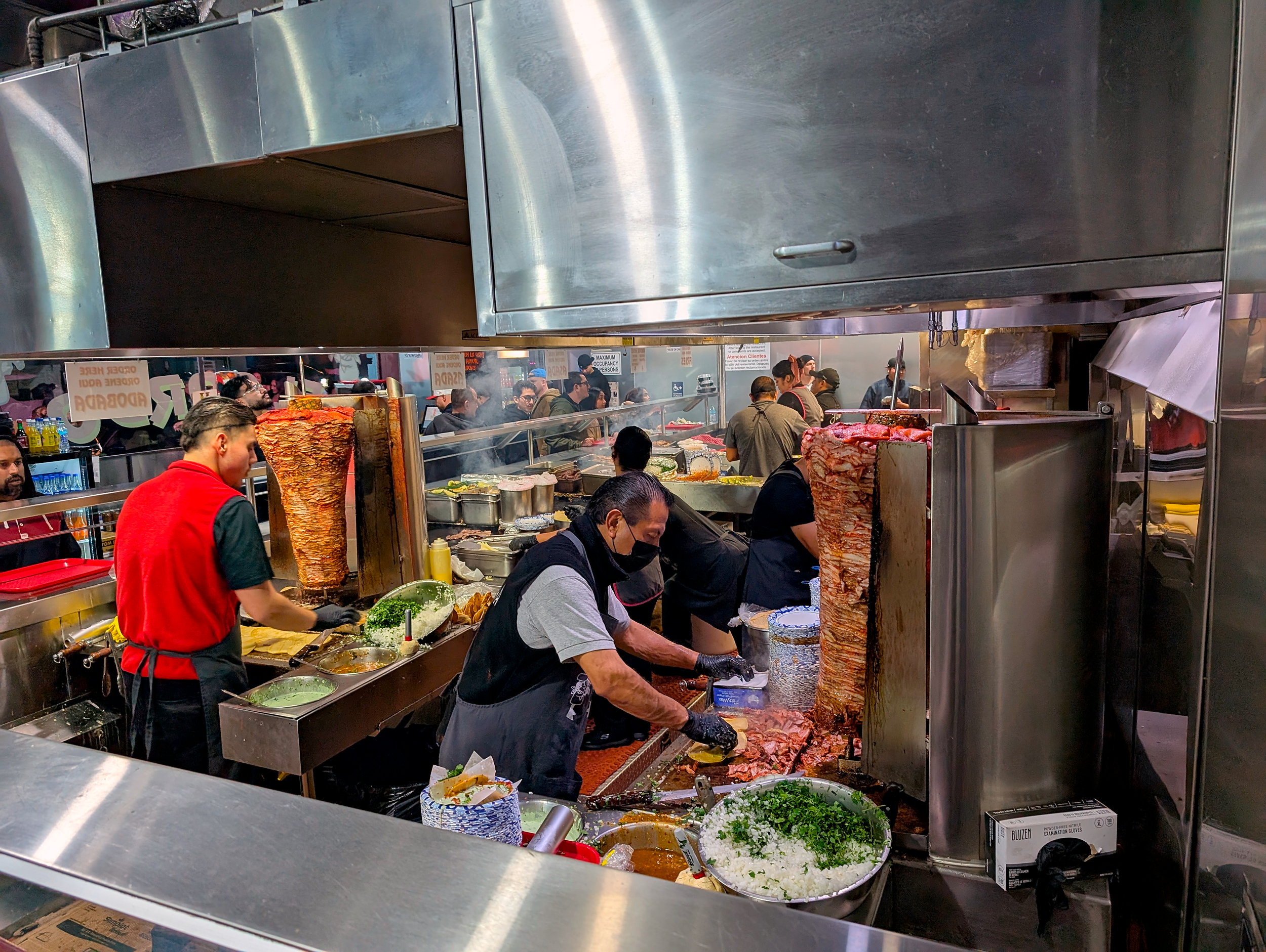 The kitchen team at Tacos El Gordo assemble tacos from el trompo