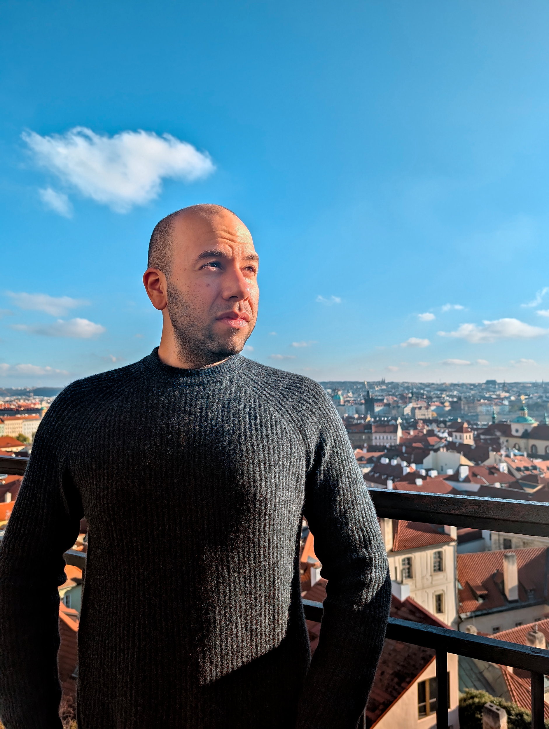 Michael wears a cashmere fisherman's rib sweater with Prague in the background