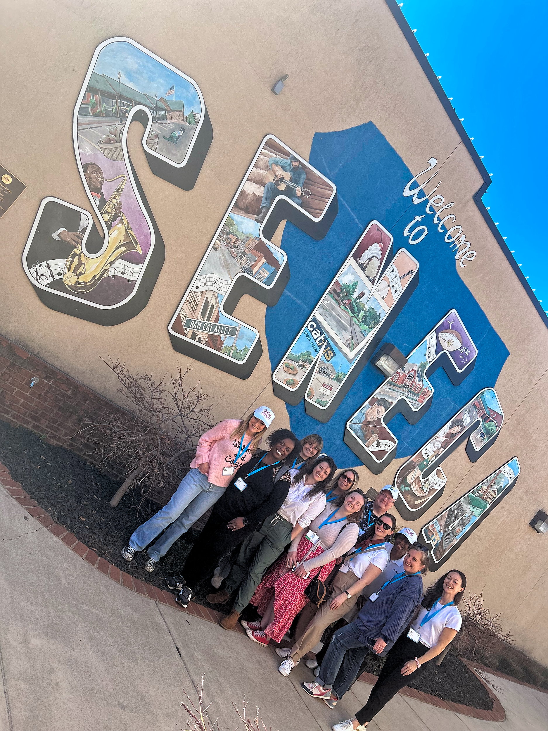 A group of people in front of a Seneca mural