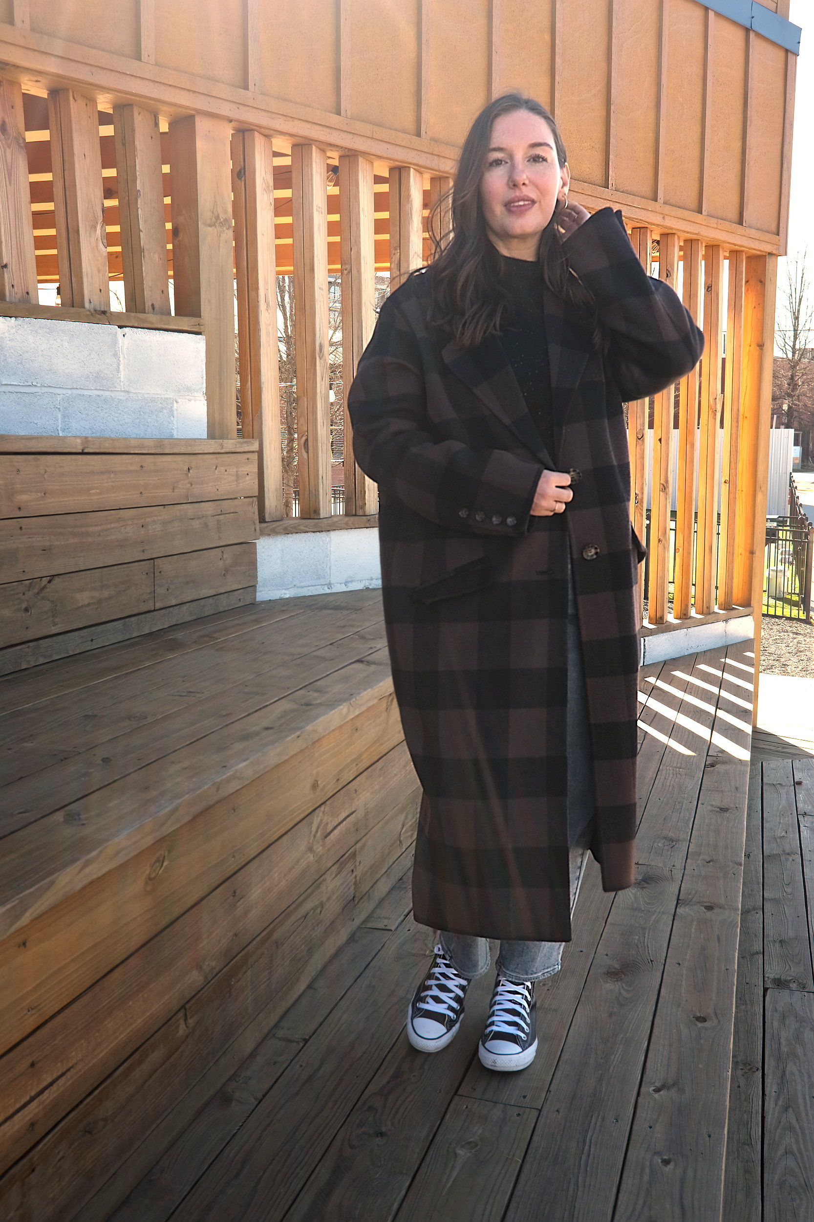 Alyssa wears a plaid coat from Universal Standard with jeans and sneakers