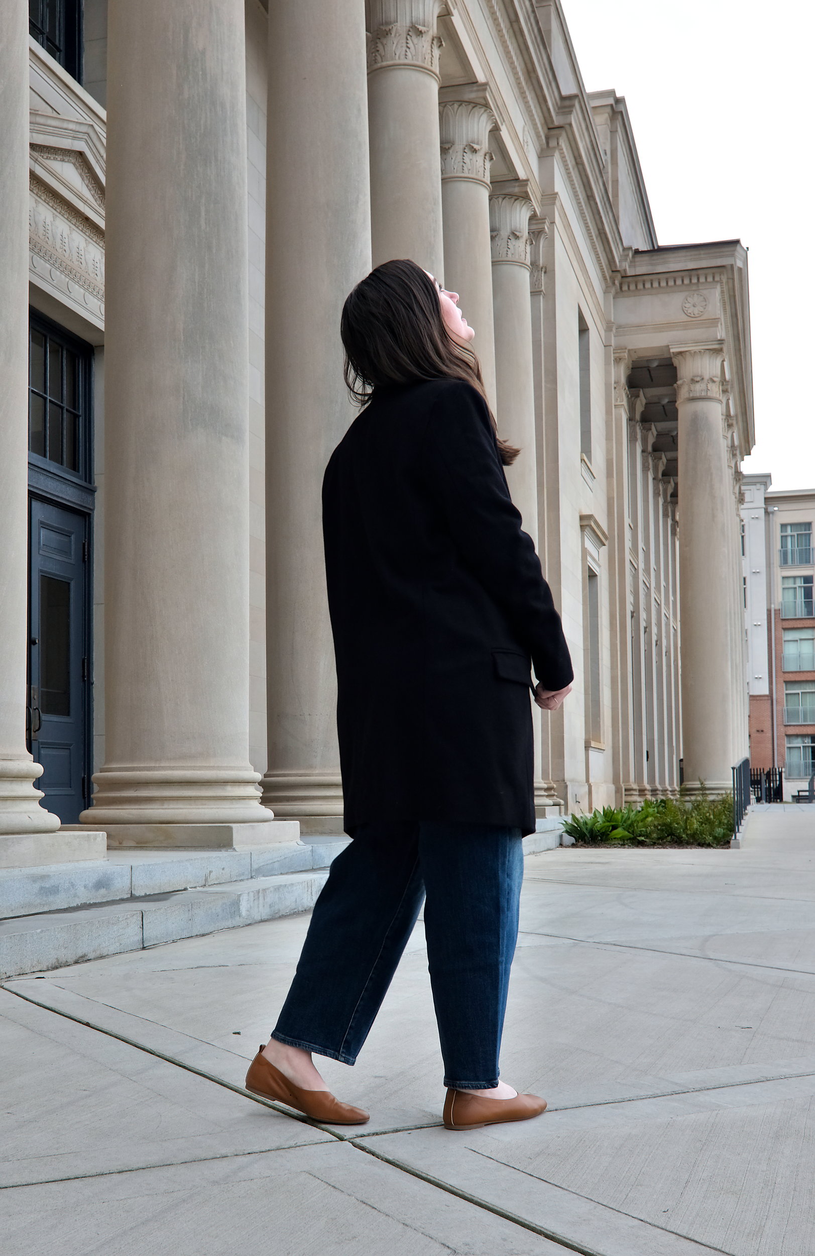 Alyssa walks away from the camera wearing a black wool coat from Universal Standard